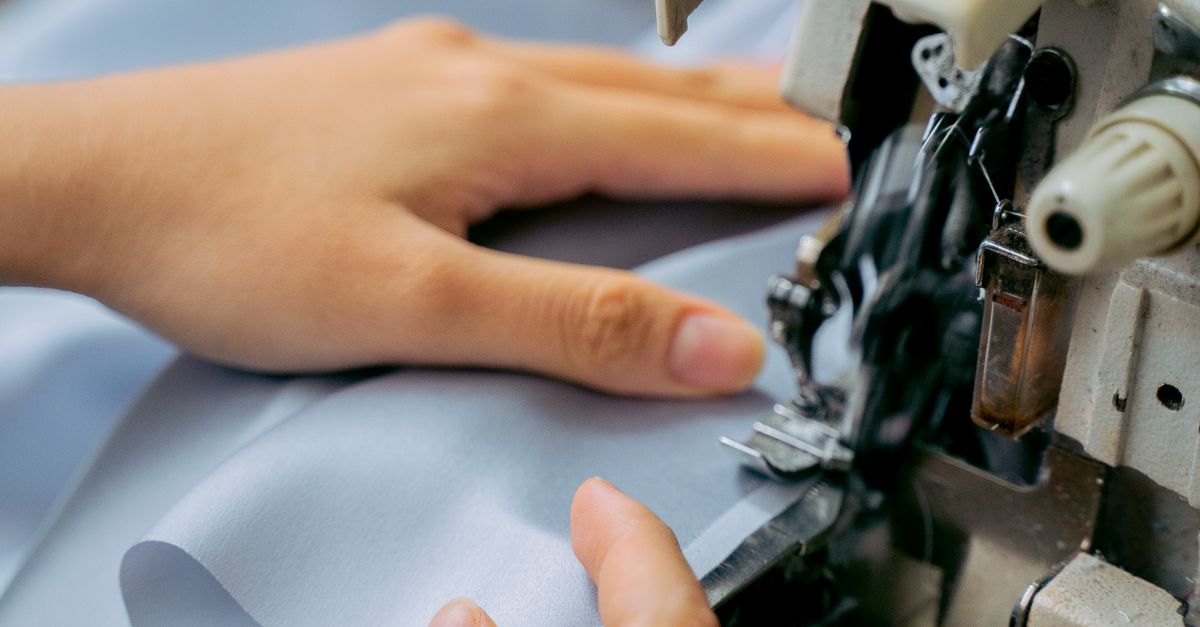 Close-up of hands sewing fabric with a sewing machine, showcasing handmade craftsmanship.