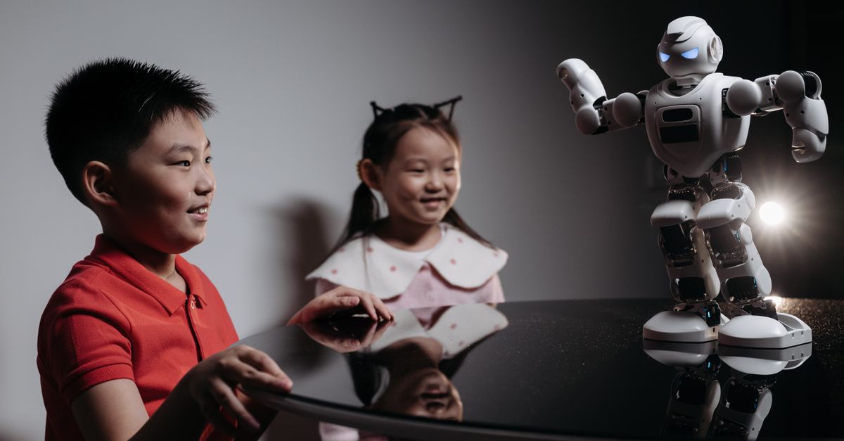 Two children interacting with a robot toy on a table, showcasing modern technology.