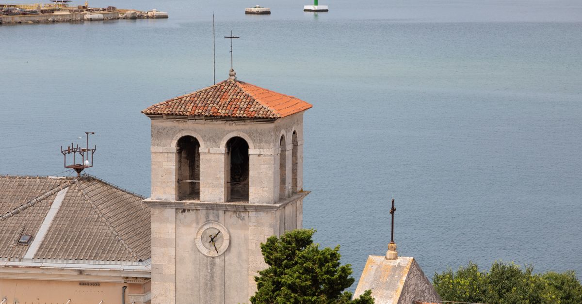 A picturesque view of a historic bell tower and rooftop by the Adriatic Sea in Pula, Croatia.