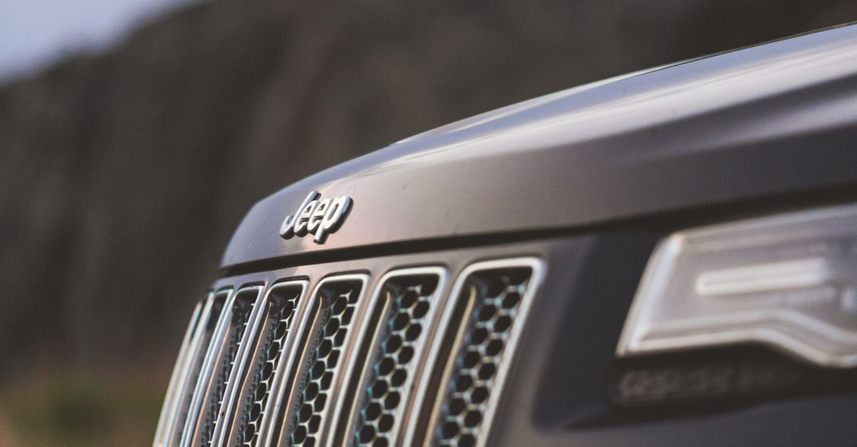 Close-up shot of a Jeep grille and headlights outdoors, emphasizing rugged design.
