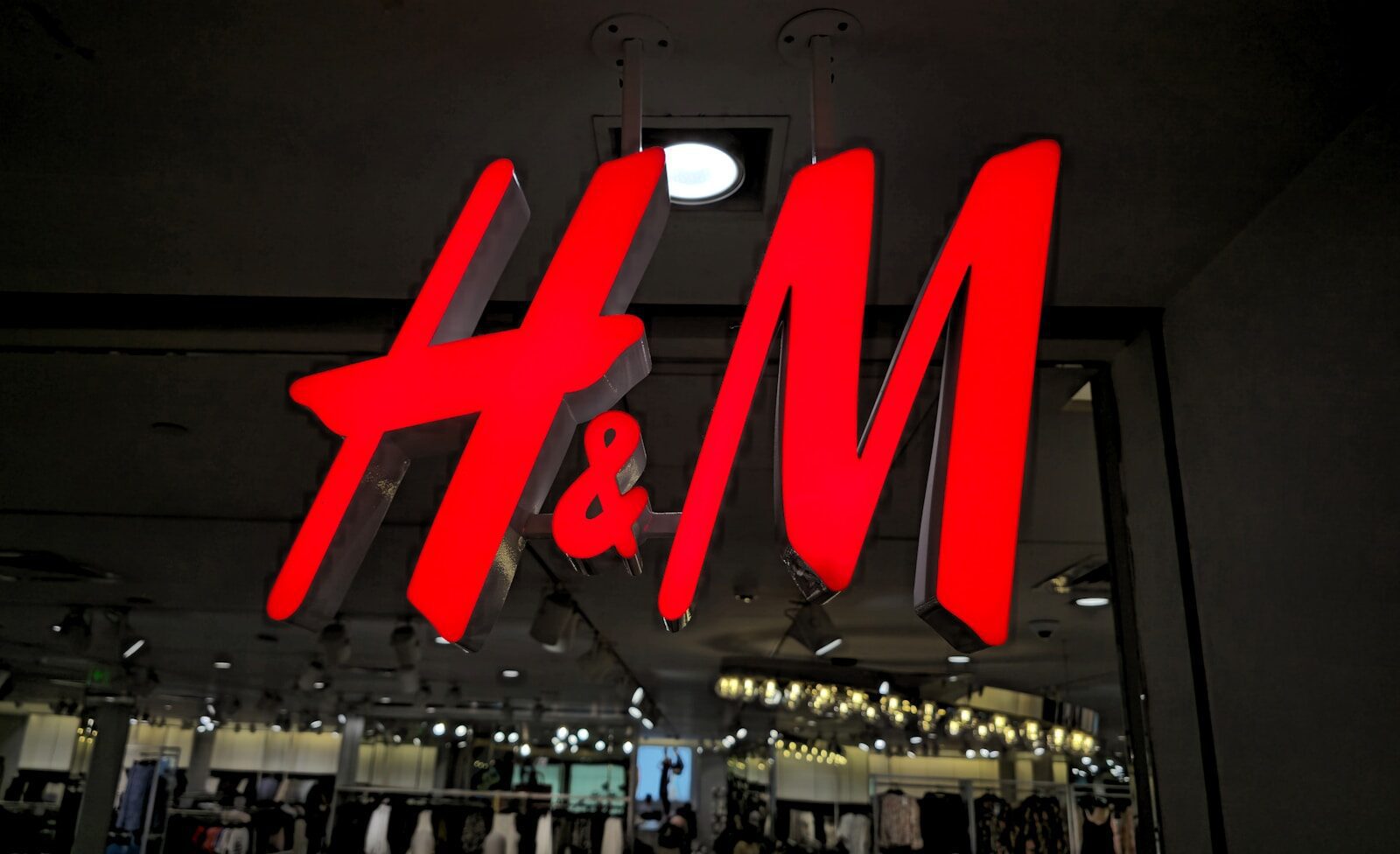 The illuminated h&m logo glows brightly at night.