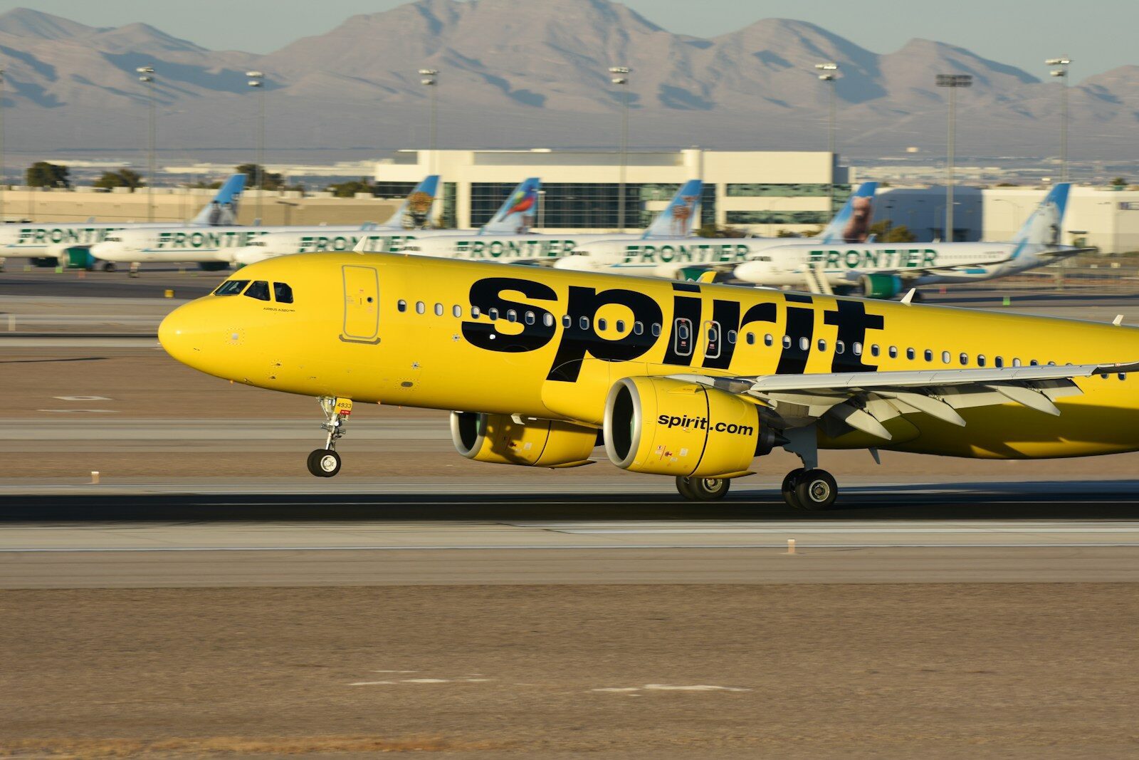 A yellow spirit airplane on the runway of an airport