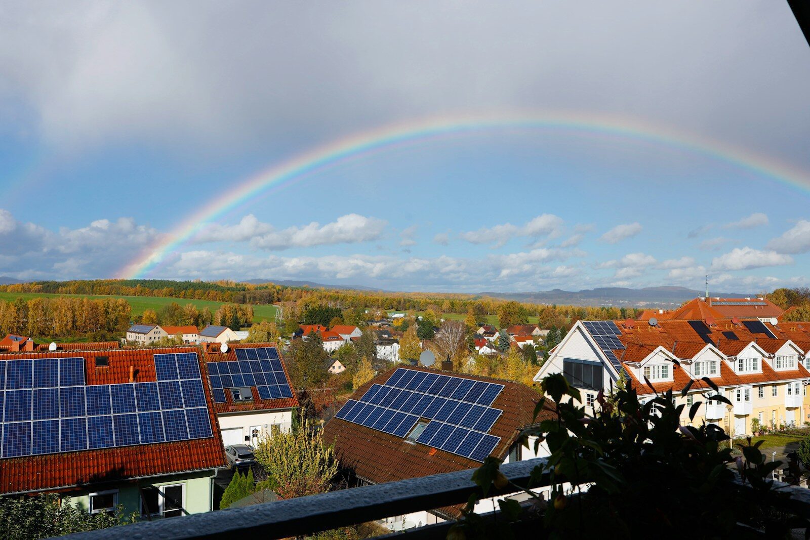 Rainbow over a suburban neighborhood with solar panels