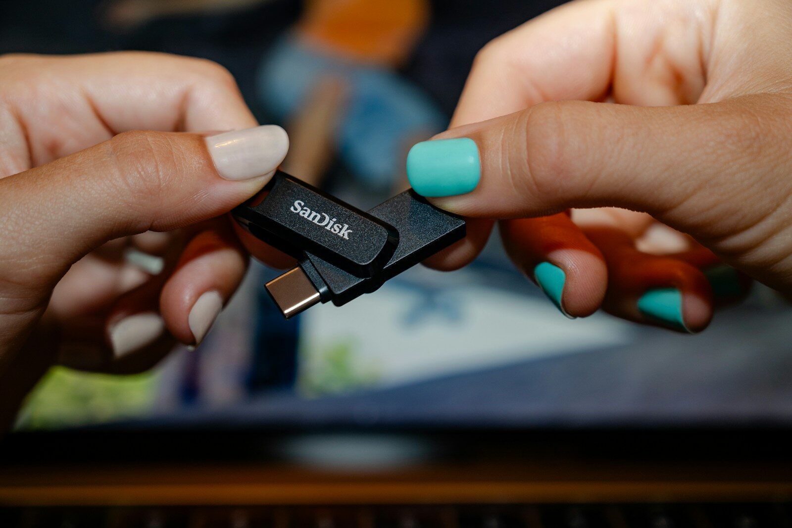 Two hands holding a sandisk usb flash drive